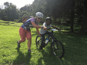 woman helps girl learn to ride bicycle