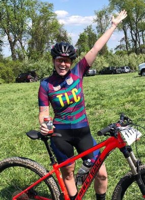 Lauren raises her hand in the air after a mountain bike race.