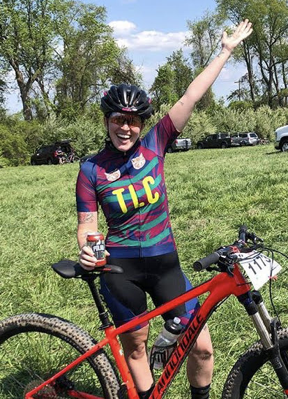 Lauren raises her hand in the air after a mountain bike race.