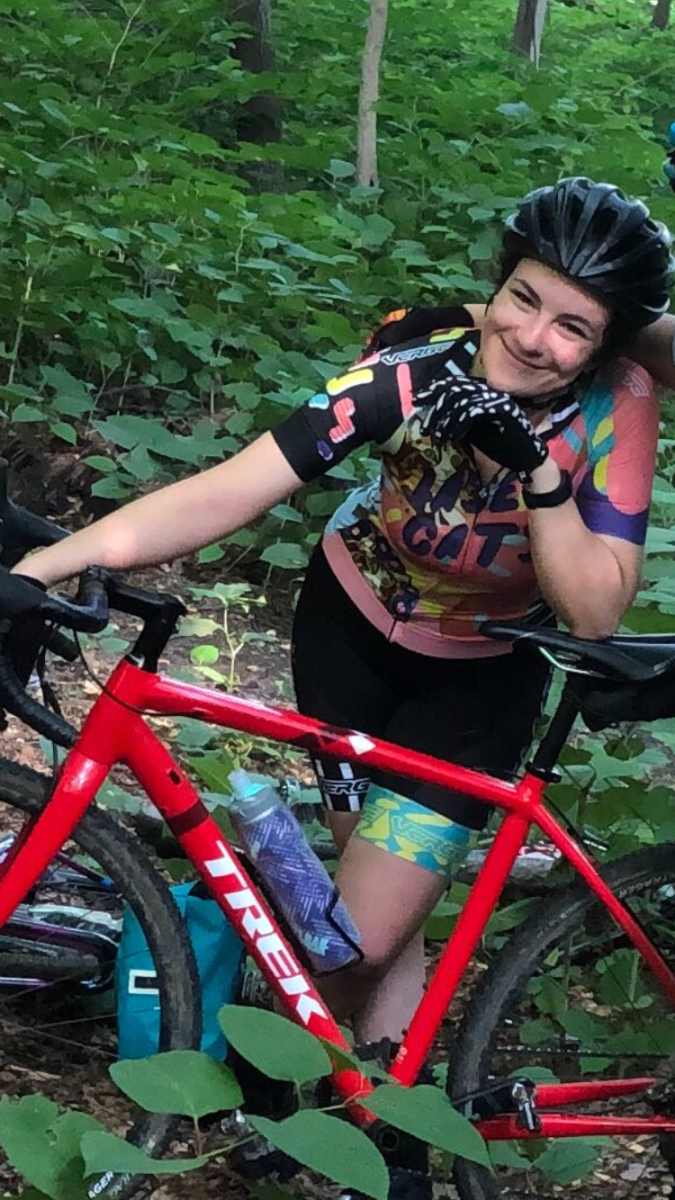 woman leans on a cyclocross bike in the woods